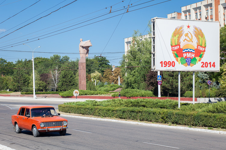 An old Russian Lada passes an anniversary sign of the Soviet state in Tiraspol