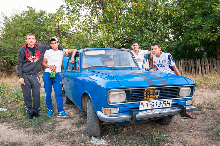Local kids are hanging out around a Moskvich car