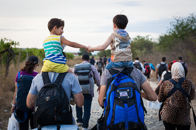 Two young Syrian boys ride on top of their fathers' shoulders after just having left Greece. For many children, the journey towards the EU seems more of an adventure because they are to young to realise the situation.