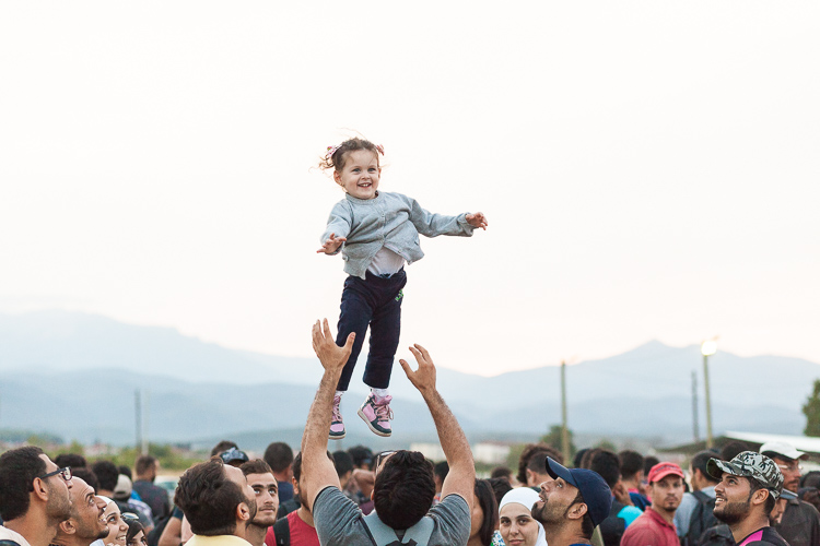 A young girl is lifted up in the air while the crowd waits to enter the Gevgelija camp in south Macedonia.