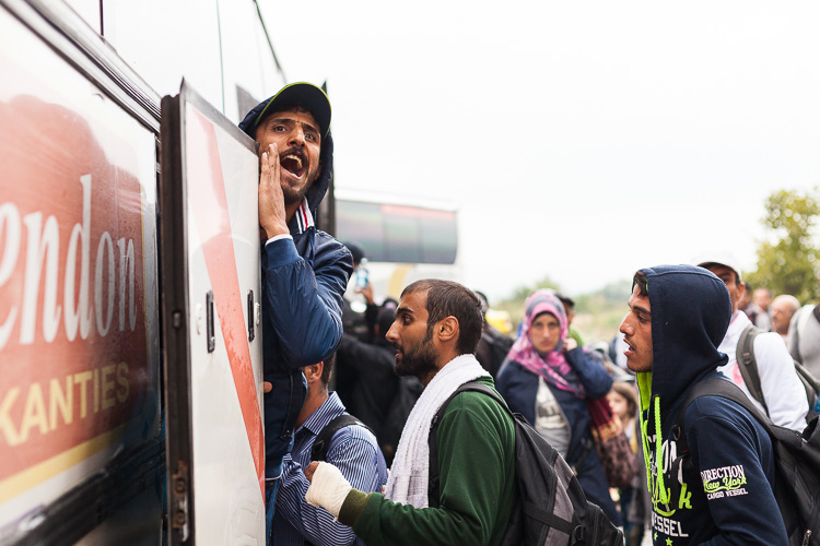 A man screams to his friends while getting on a bus during a day of railway strike.