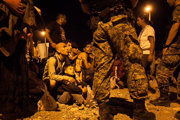A child and his father sit down as they obey orders given to them by Macedonian soldiers, before boarding a night train towards Tabanovce.