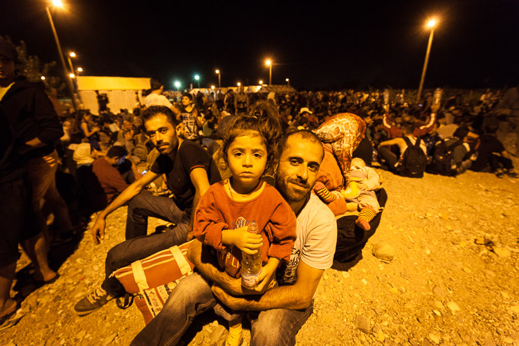 A father and child sit down in Gevgelija camp as they are waiting with 1000 others to board a train that brings them directly to the northern border town Tabanovce.