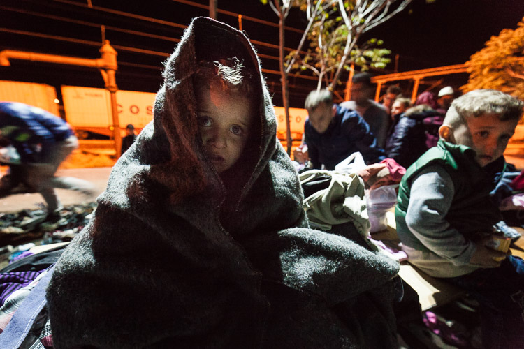 A child, wrapped up warmly by volunteers, cries for his mother at 3AM after arriving in Tabanovce.