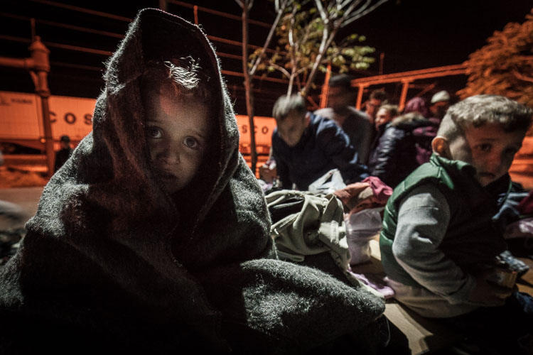 A child, wrapped up warmly by volunteers, cries for his mother at 3AM after arriving in Tabanovce, north Macedonia..